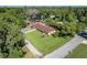 Aerial view of a home with a large, grassy front yard, mature trees, and a carport on the side of the property at 3048 Mango Tree Dr, Edgewater, FL 32141