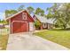Charming red home with matching detached garage with lush greenery and a quaint yard at 3222 Juniper Dr, Edgewater, FL 32141