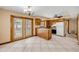 Cozy kitchen featuring wood cabinets, white appliances, tiled floors, and sliding glass doors to the outdoor pool area at 3222 Juniper Dr, Edgewater, FL 32141