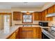 Bright kitchen with wood cabinetry, stainless appliances, tile countertops, and an eye-catching window fixture at 3222 Juniper Dr, Edgewater, FL 32141
