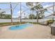 A screened kidney shaped pool sits on a spacious concrete patio with a metal bench and grill nearby at 3222 Juniper Dr, Edgewater, FL 32141