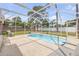 A screened kidney shaped pool sits on a concrete patio with metal rails for entry in a sunny backyard at 3222 Juniper Dr, Edgewater, FL 32141