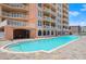 Resort-style pool with brick pavers, blue water, and condo balconies at 3245 S Atlantic Ave # 208, Daytona Beach, FL 32118