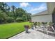 Lush backyard with green grass and a stone patio featuring lounge chairs and potted plants at 3378 Leonardo Ln, New Smyrna Beach, FL 32168