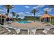 Community pool area with palm trees, lounge chairs, and views of the buildings at 4620 Riverwalk Village Ct # 7306, Ponce Inlet, FL 32127