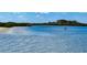Relaxing water view of small boat on calm water with trees, plants, and a beach shoreline at 4620 Riverwalk Village Ct # 7306, Ponce Inlet, FL 32127