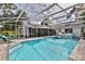 Beautiful screened-in pool with sun loungers and tropical landscaping with a brick paver deck at 475 Spruceview Dr, Port Orange, FL 32127