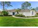 Charming single-story home featuring a lush green lawn, tropical landscaping and a bright blue front door at 484 Sweet Bay Ave, New Smyrna Beach, FL 32168