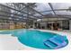 Large screened-in pool with blue water and an inflatable float; view of house at 484 Sweet Bay Ave, New Smyrna Beach, FL 32168