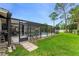 Screened pool area with patio seating, surrounded by lush landscaping and a well-maintained lawn at 484 Sweet Bay Ave, New Smyrna Beach, FL 32168