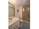 Well-lit bathroom featuring a glass-enclosed shower, a classic white vanity, toilet, and a large mirror at 4849 Saxon # C202, New Smyrna Beach, FL 32169