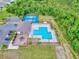 An aerial view shows the community pool and tennis courts surrounded by lush green landscaping and ample parking at 534 Stowers Dr, New Smyrna Beach, FL 32168