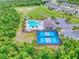 Aerial view of community amenities: pool, cabana, pickleball courts and parking area, surrounded by trees at 534 Stowers Dr, New Smyrna Beach, FL 32168