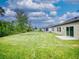 Backyard with green lawn, landscaping, and a back view of the home at 534 Stowers Dr, New Smyrna Beach, FL 32168
