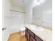 Bright bathroom features a granite vanity, framed mirror, wood plank flooring, and tub with white tile surround at 534 Stowers Dr, New Smyrna Beach, FL 32168