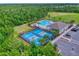Aerial view showcasing community pool, clubhouse, pickleball courts, parking, and green spaces within a wooded area at 534 Stowers Dr, New Smyrna Beach, FL 32168