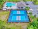 Aerial view of community pickleball courts next to a pool, clubhouse, and parking area, surrounded by lush landscaping at 534 Stowers Dr, New Smyrna Beach, FL 32168
