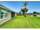 Backyard view featuring manicured lawn, palm tree, screened patio and home exterior along lake at 535 Coral Trace Blvd, Edgewater, FL 32132