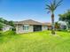 Backyard showcasing a well-maintained lawn, palm tree, and the exterior of the brick home at 535 Coral Trace Blvd, Edgewater, FL 32132