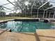 Inviting pool area with screened enclosure and waterfall feature, surrounded by well-maintained landscaping at 547 Cleo Ln, Deltona, FL 32738
