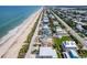 Expansive aerial shot showcasing beachfront homes along a sandy coast at 6320 S Atlantic Ave, New Smyrna Beach, FL 32169