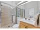 Bathroom featuring a tiled shower with glass doors, toilet, single sink vanity and large mirror at 6320 S Atlantic Ave, New Smyrna Beach, FL 32169