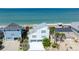 Aerial view of a charming light blue beach house, complemented by lush landscaping and ocean views at 6871 S Atlantic Ave., New Smyrna Beach, FL 32169