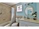 Bathroom with vanity, round mirror, and shower with tile surround and nautical decor at 6871 S Atlantic Ave., New Smyrna Beach, FL 32169