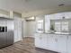 Open kitchen view featuring white cabinets, granite countertops, stainless steel fridge, and wood flooring at 7 Heather Ln, Ormond Beach, FL 32174