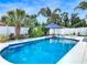 Backyard pool featuring an umbrella and tropical landscaping behind a white fence at 7 Heather Ln, Ormond Beach, FL 32174