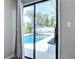 Backyard pool view through glass door, framed by lush landscaping and comfortable seating at 7 Heather Ln, Ormond Beach, FL 32174