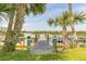 Dock with lush green grass and palm trees lead to the waterfront at 76 Heather Point Ct, New Smyrna Beach, FL 32169