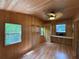 Comfortable bedroom with natural wood walls, ceiling fan, and built-in desk space at 125 Rio Vista Dr, Edgewater, FL 32132