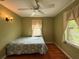 A cozy bedroom with hardwood floors, neutral paint color, two windows, and a ceiling fan at 125 Rio Vista Dr, Edgewater, FL 32132