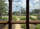 A picturesque window view framing lush greenery, palm trees, and a bright, inviting sidewalk at 125 Rio Vista Dr, Edgewater, FL 32132