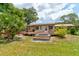 Home's backyard shows patio, stairs, deck, hot tub, landscaping and mature trees at 130 N Gaines St, Oak Hill, FL 32759