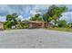 Single-story home features gravel landscaping, metal carport and partial fence in a rural setting at 130 N Gaines St, Oak Hill, FL 32759