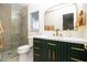 Stylish bathroom with glass shower, decorative mirror, and vanity with green cabinets and gold hardware at 1327 Wayne Ave, New Smyrna Beach, FL 32168