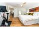 Bedroom with wood floors, a white bedspread, and view of the kitchen and living spaces at 1327 Wayne Ave, New Smyrna Beach, FL 32168