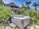 Backyard featuring a luxurious hot tub amidst lush landscaping and a multi-story home at 1421 N Atlantic Ave, New Smyrna Beach, FL 32169
