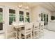 Dining area featuring a large table, white chairs, pendant lighting, and views of the outdoor space at 150 Portofino Blvd, New Smyrna Beach, FL 32168