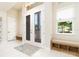 Bright foyer with double glass doors, accent benches, transom window, and views of landscaped exterior at 150 Portofino Blvd, New Smyrna Beach, FL 32168