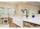 Bright kitchen island with white countertops, farmhouse sink, stainless steel appliances, and views of the patio at 150 Portofino Blvd, New Smyrna Beach, FL 32168