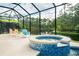 Enclosed pool area featuring a blue tiled hot tub and seating overlooking a serene pond and wooded area at 150 Portofino Blvd, New Smyrna Beach, FL 32168