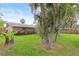 Lush backyard featuring a privacy fence, mature trees, and a view of the home's exterior and wooden deck at 1723 Needle Palm Dr, Edgewater, FL 32132