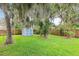 Well-manicured backyard showcases a storage shed and mature trees at 1723 Needle Palm Dr, Edgewater, FL 32132