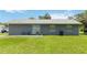 A backyard view, featuring a residence with a gray exterior, green grass, and clear blue sky at 1920 Travelers Palm Dr, Edgewater, FL 32141