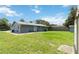 Spacious backyard view featuring a well-maintained lawn and a residence with a gray exterior and a patio at 1920 Travelers Palm Dr, Edgewater, FL 32141