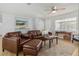 Comfortable living room with leather furniture, ceiling fan, and bright natural light from the window at 1920 Travelers Palm Dr, Edgewater, FL 32141