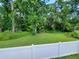 The lush backyard, surrounded by a white fence and mature trees, providing a private oasis at 1941 Spruce Creek Lndg, Port Orange, FL 32128